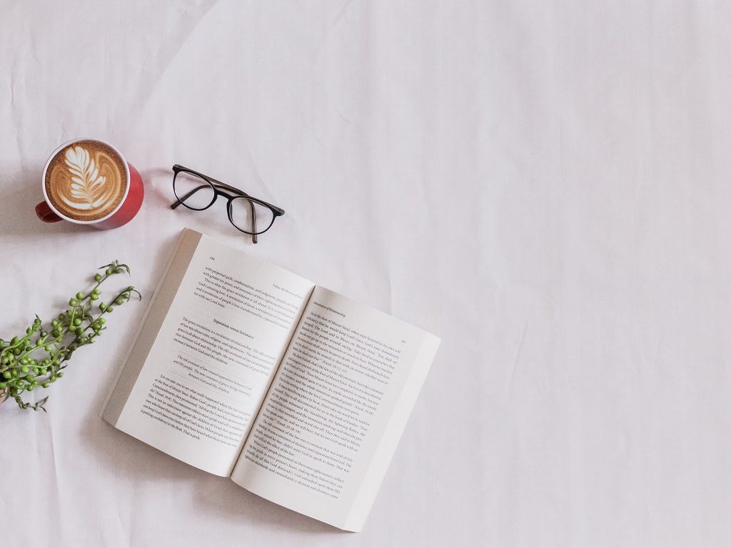 Opened book and glasses placed on the sofa.