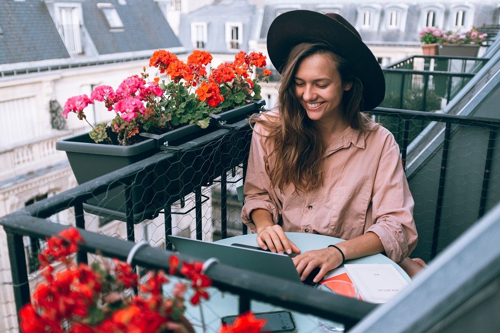 Girl sitting and working with her personal writer on balcony 