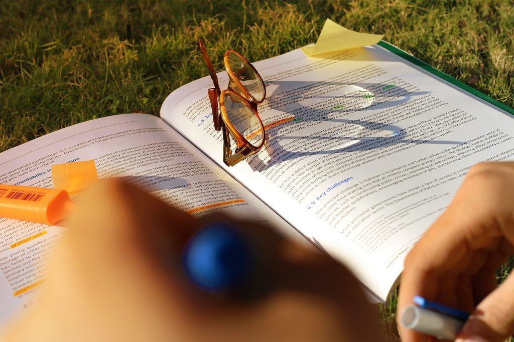 A book and glasses and a pen for lightening the text 