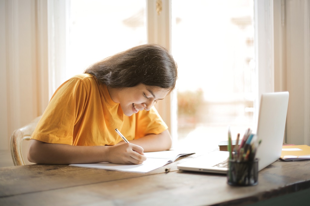 Student girl writing essay in her notebook.